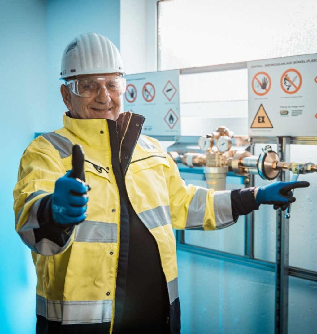 Techniker steht vor einer geprüften Gasinstallation und signalisiert ein erfolgreiches Ergebnis.