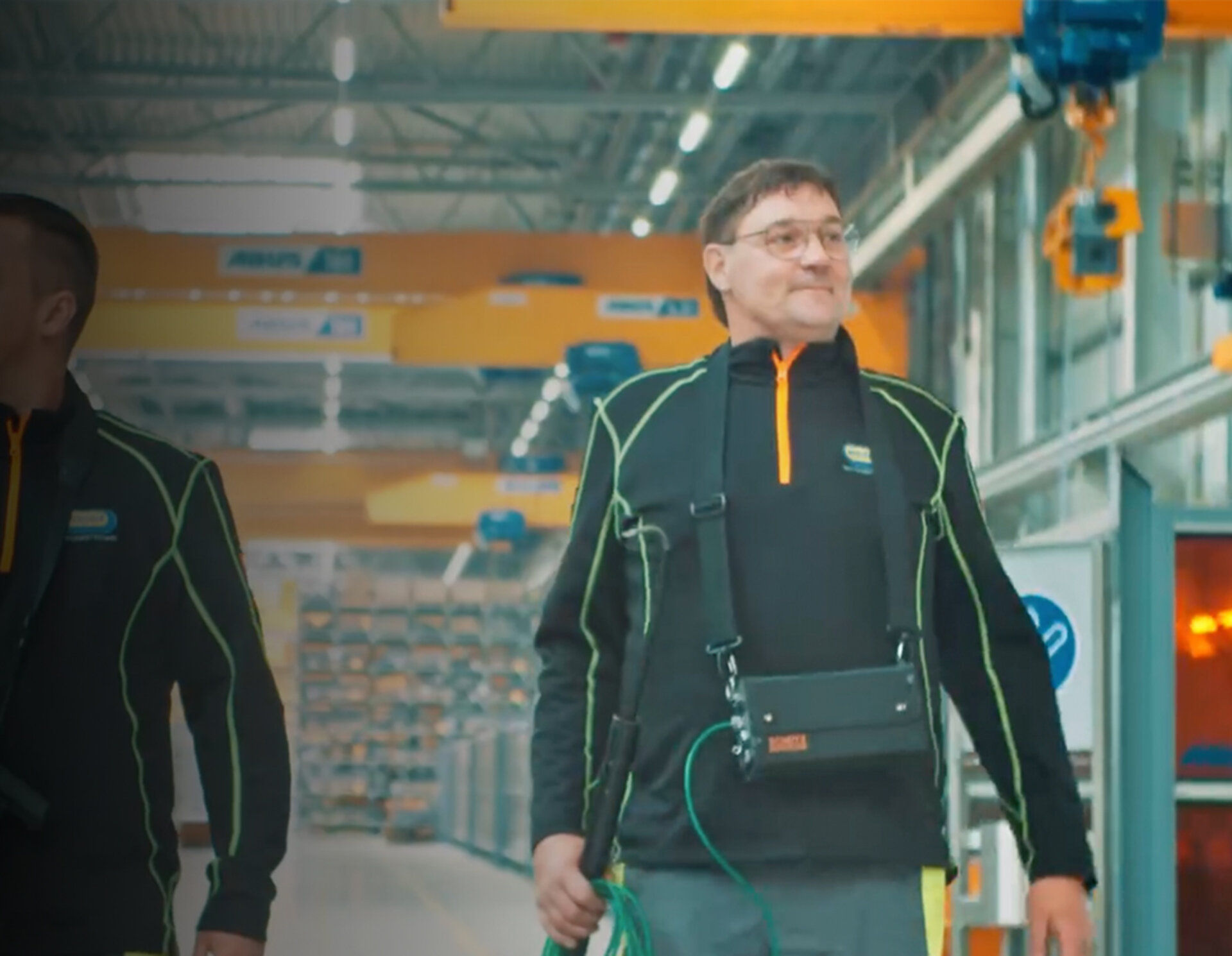 Zwei Techniker prüfen Industrieanlagen mit mobilen Messgeräten in einer modernen Produktionshalle