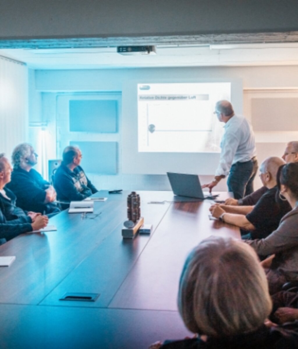 Trainer präsentiert Inhalte vor einer Gruppe Teilnehmender während einer technischen Schulung im Meetingraum.
