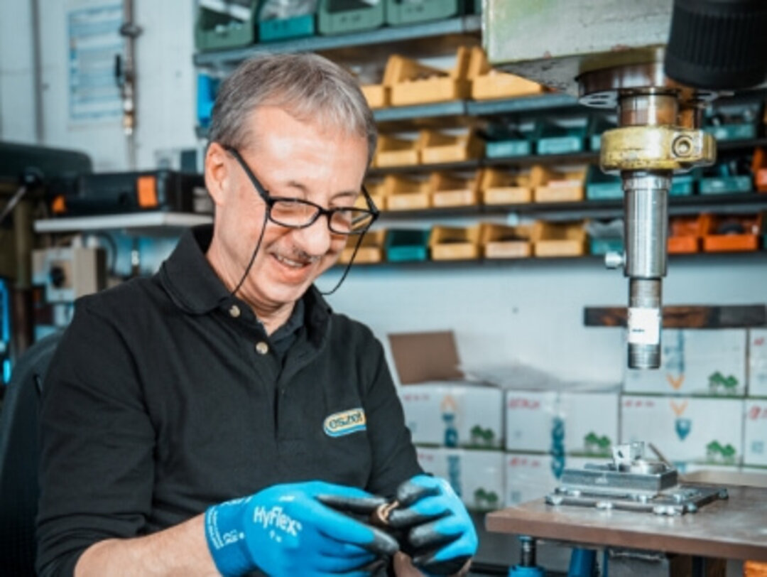 Mitarbeiter bearbeitet ein Bauteil an seinem Arbeitsplatz und führt einen präzisen Arbeitsschritt aus.