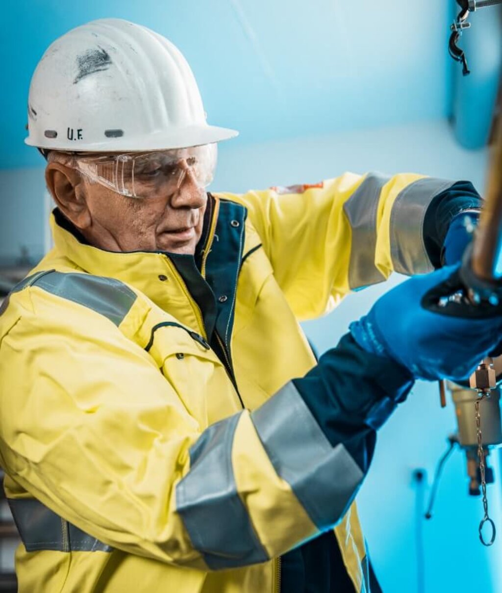 Techniker in Schutzkleidung überprüft eine Gasanlage und arbeitet konzentriert an sicherheitsrelevanten Bauteilen.