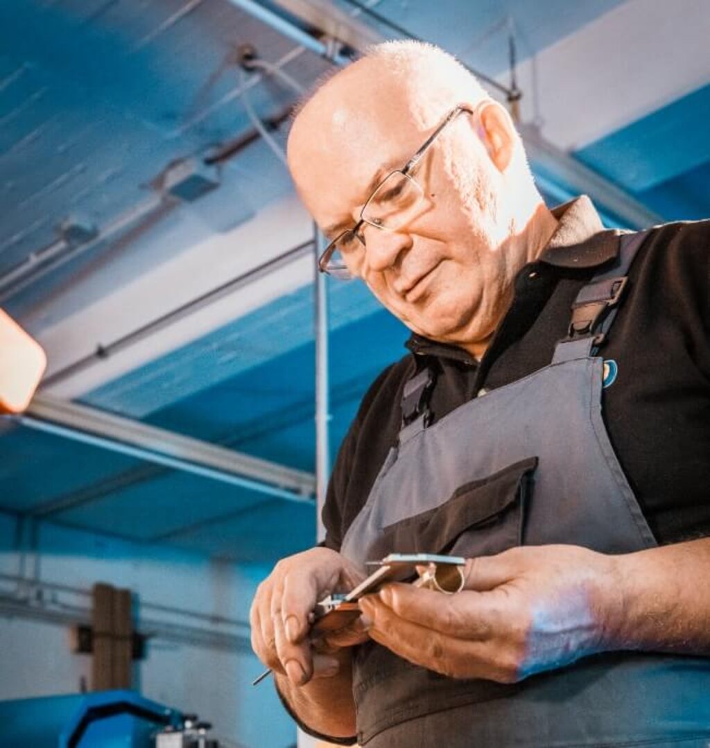 Mitarbeiter überprüft ein Bauteil manuell im Rahmen der Qualitätskontrolle.