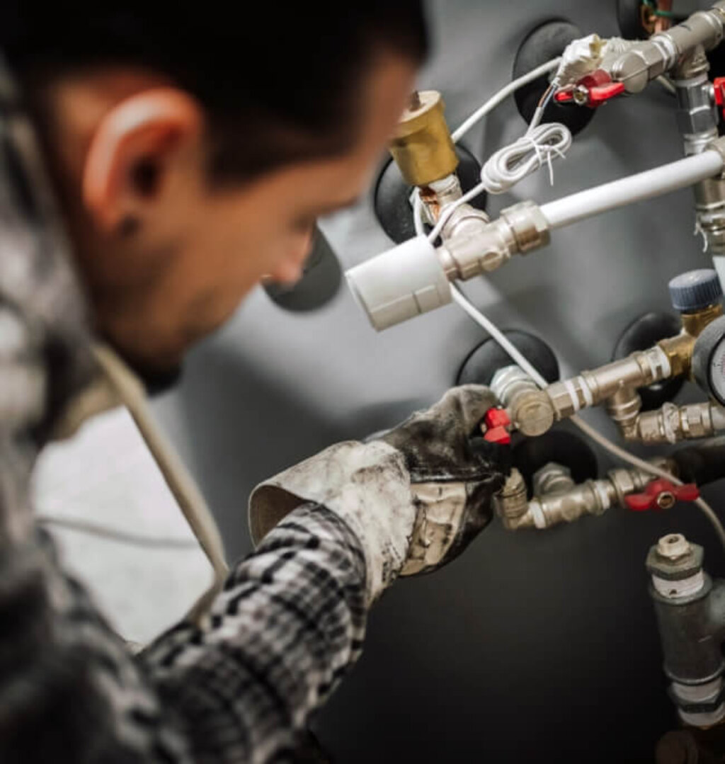 Handwerker arbeitet an Leitungsarmaturen und stellt Anschlüsse ein