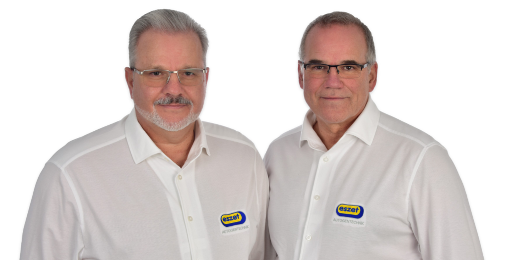 Die Zwei Geschäftsführer Olaf Brückmann und Michael Brückmann stehen nebeneinander und blicken freundlich in die Kamera in professioneller Pose.